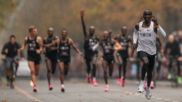 Eliud Kipchoge approaches the finish line, with his pacemakers celebrating behind. 