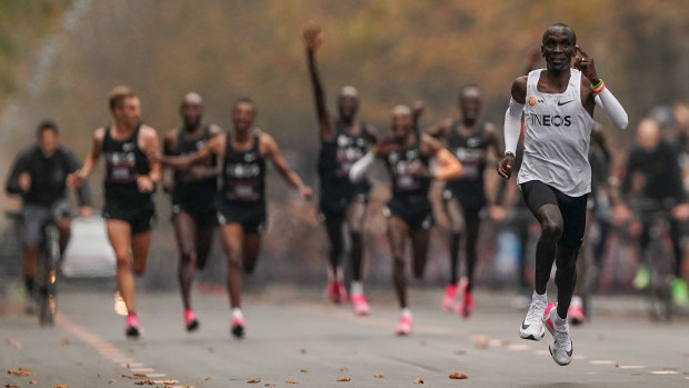 Eliud Kipchoge approaches the finish line after running 1:159 in a marathon in 2019, with his pacemakers celebrating behind. 