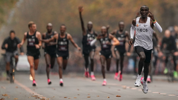 Eliud Kipchoge approaches the finish line, with his pacemakers celebrating behind. 