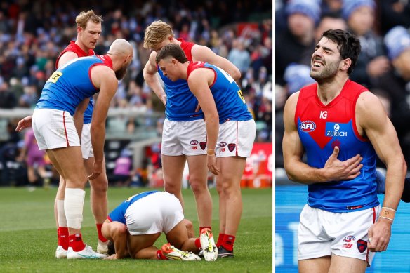 Demons players huddle around injured teammate Christian Petracca, before he leaves the field with a rib injury (right).