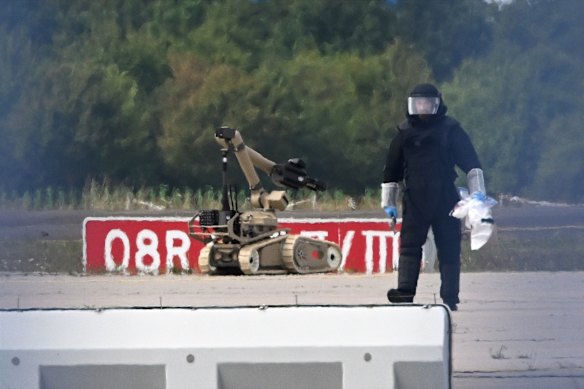 A forensic technician works alongside a bomb-disposal robot at Leipzig-Halle Airport.