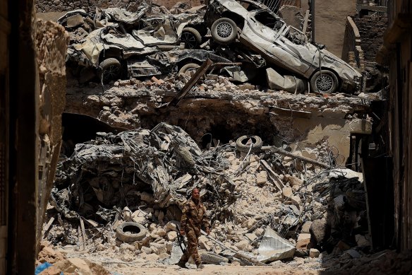 An Iraqi soldier walks past a wall of debris on June 30, 2017, during the violent campaign to retake the city of Mosul from ISIS.