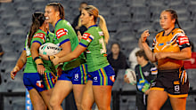 Raiders players celebrate a try against the Wests Tigers.
