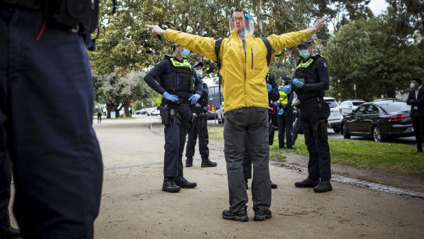 An anti-lockdown supporter is questioned by Victoria Police.