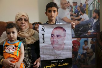 Amal el-Halabi, 57, holds her grandson Fares, 18 months, while another grandson Amro, 7, holds a picture of his father Mohammed el-Halabi, at the family home in Gaza City.  The Arabic on the picture reads: “The man of humanity”.