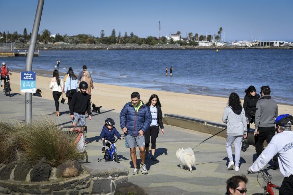 Pedestrians walk along the beach on a unseasonably warm autumn day. 