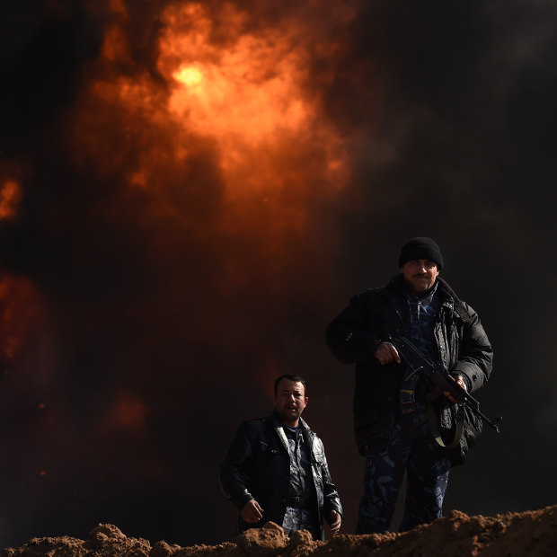 Two men provide security at Well 77 in the Qayyarah oil fields outside Mosul. Islamic State blew the wells up as they retreated.