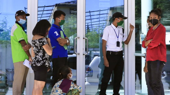 People wearing protective face masks queue to enter a shopping center in Dili, East Timor last week. 