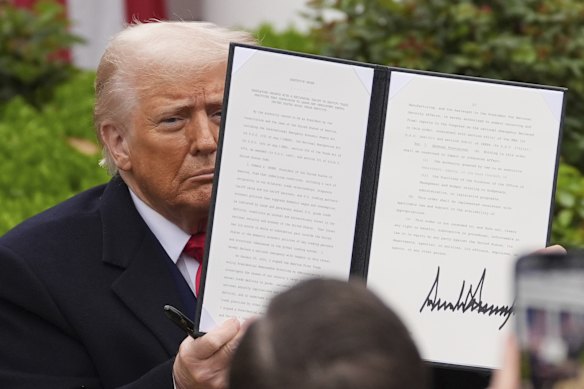 President Donald Trump holds a signed executive order during an event to announce new tariffs. 