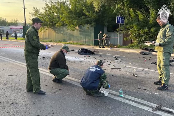 In a photo taken from video released by Investigative Committee of Russia on Sunday, investigators at the site of an explosion of a car driven by Daria Dugina outside Moscow. 