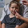Dr Annalyse Crane giving three-year-old Hamish Gray his first nasal spray flu vaccine at Family Medical Practice in Kirrawee, alongside his father, Ben. 