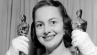 Olivia de Havilland holds two Oscars as she returns home following the Academy Awards Presentations, 1950.