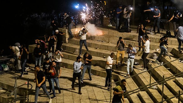 Palestinians escape from a stun grenade fired by Israeli police officers during clashes at Damascus Gate during Ramadan in Israeli-occupied East Jerusalem.