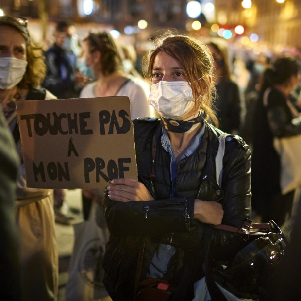 A woman holds a sign reading "Do not touch my teacher" during a national tribute to Samuel Paty in Paris. 