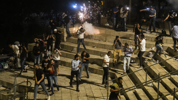 Palestinians escape from a stun grenade fired by Israeli police officers during clashes at Damascus Gate during Ramadan in Israeli-occupied East Jerusalem.
