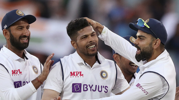 India's Umesh Yadav, centre, is congratulated by his captain Virat Kohli, right, after the wicket of Australia's Pat Cummins.