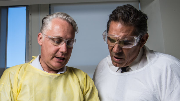 Professor Michael Buckland from the Concussion Legacy Foundation and former NFL player Colin Scotts examine a brain.