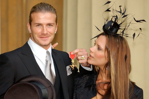 David Beckham with wife Victoria, as he holds the OBE he received in November 2003.