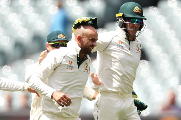 Nathan Lyon, left, celebrates with Tim Paine  after taking the wicket of Shan Masood. 