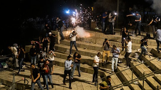 Palestinians escape from a stun grenade fired by Israeli police officers during clashes at Damascus Gate during Ramadan in Israeli-occupied East Jerusalem on May 8.
