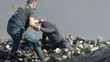 Un funcionario de The Guardian ayuda a sacar botellas de vidrio de debajo de un contenedor en Melilla, España.