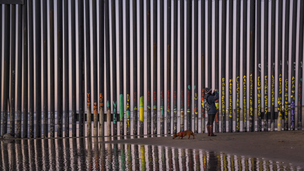A woman takes a snapshot by the border fence between San Diego, California, and Tijuana, as seen from Mexico. 
