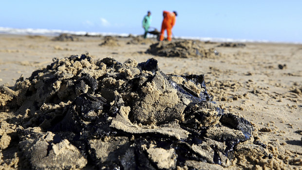 Workers remove oil from Viral Beach, in Aracaju, Brazil. 