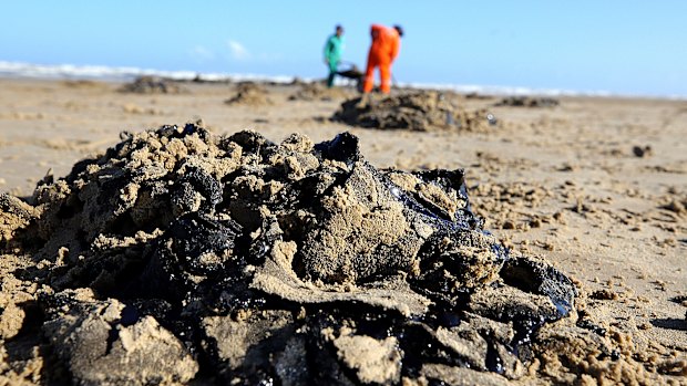 Workers remove oil from Viral Beach, in Aracaju, Brazil. 