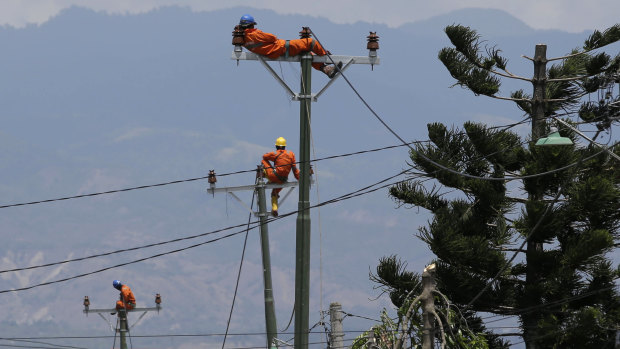 Workers take a break as they restore electricity in earthquake-hit Balaroa, Palu.