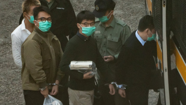 Pro-democracy activists Joshua Wong, centre, and Ivan Lam, left, board a Hong Kong Correctional Service van ahead of a sentence hearing on Wednesday.