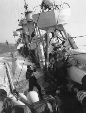 HMAS Vendetta in a heavy sea, with her gunnery officer secured by a lifeline.