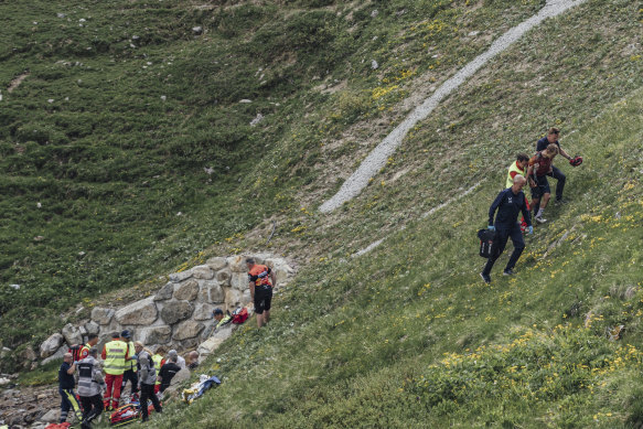 Switzerland’s Gino Mäder, left, receives medical attention after crashing as Magnus Sheffield of the United States, right, is helped away.