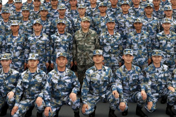 Chinese President Xi Jinping (centre in green uniform) poses with soldiers on a navy ship in 2018.