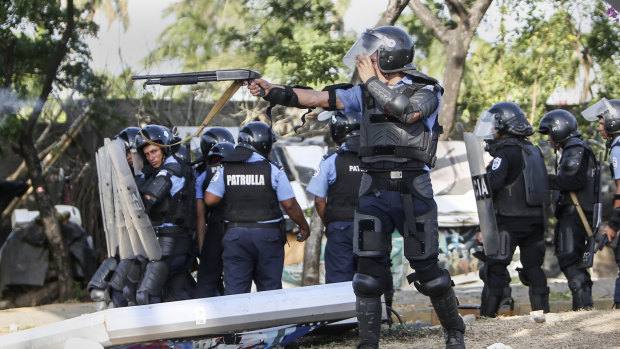 A Nicaraguan police officer aims his weapon at protesting students on Friday.