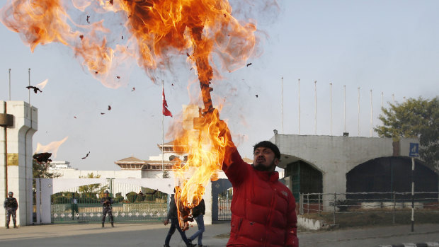 A Nepalese protester burns an effigy of Prime Minister Khadga Prasad Oli in front of the parliament building in Kathmandu on Sunday.