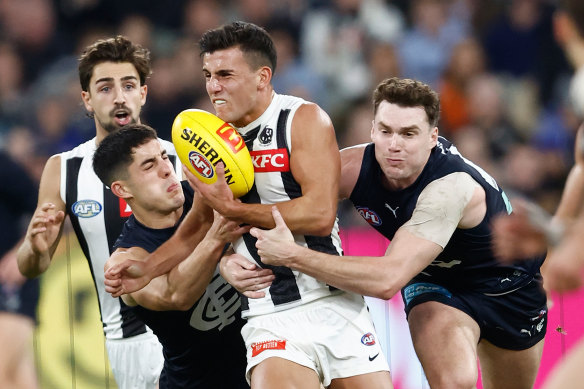 Nick Daicos of the Magpies is tackled by Adam Cerra (left) and Blake Acres of the Blues.