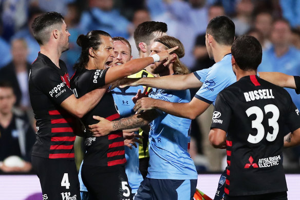 Daniel Georgievski clashes with Sydney FC players during a controversial end to the last derby two weeks ago.