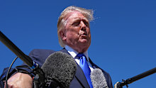 US President Donald Trump talks with reporters after an emergency inflatable slide deployed on Air Force One.