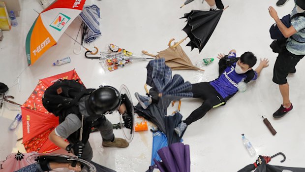 A police officer scuffles with protesters in a shopping mall in Sha Tin district in Hong Kong on Sunday.