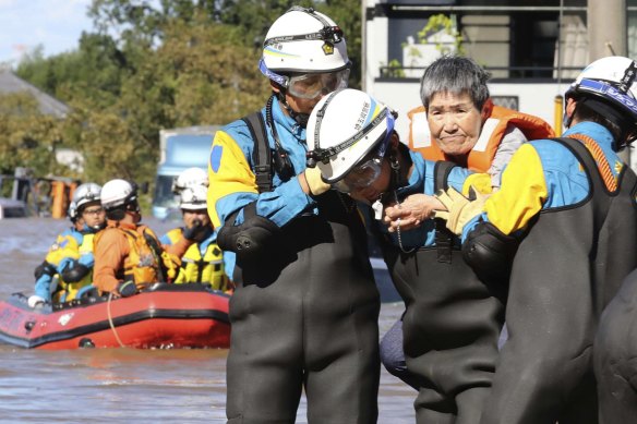An elderly woman, who stayed at an intensive nursing home isolated by the Typhoon Hagibis, is rescued by local firefighters and police officers in Kawagoe, Saitama Prefecture.