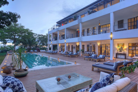 A central dining and lounge area wraps around a chequerboard-bottomed pool.