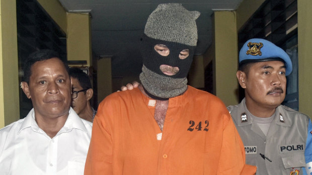 Police officers escort an Australian man at a local police headquarters in Denpasar, Bali.