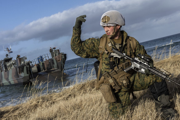 A US marine waves his troops onward after using Dutch landing craft to land near Sandstrand, Norway, March 21, 2022, during the Exercise Cold Response earlier this year.
