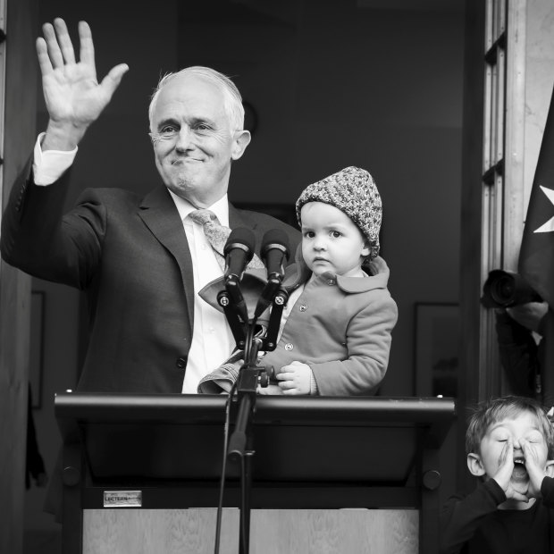 Malcolm Turnbull, holding granddaughter Alice, waves goodbye as grandson Jack plays with the media. 