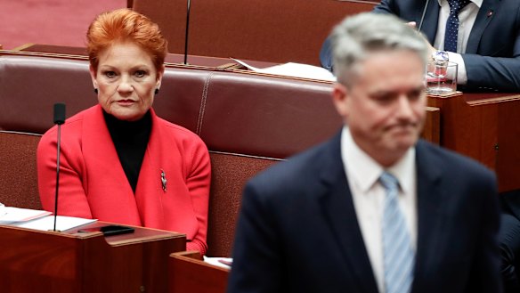 Minister for Finance Mathias Cormann walks back to his seat after speaking with Senator Pauline Hanson in June. 