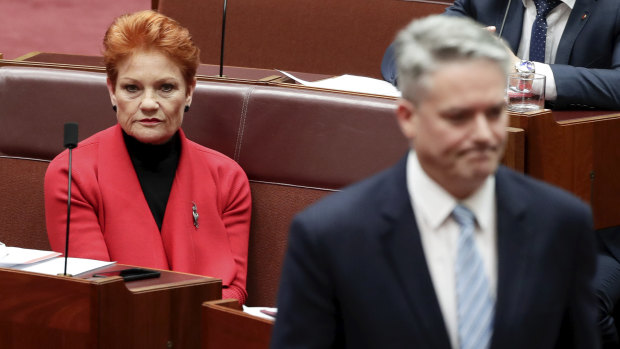 Minister for Finance Mathias Cormann walks back to his seat after speaking with Senator Pauline Hanson in June. 