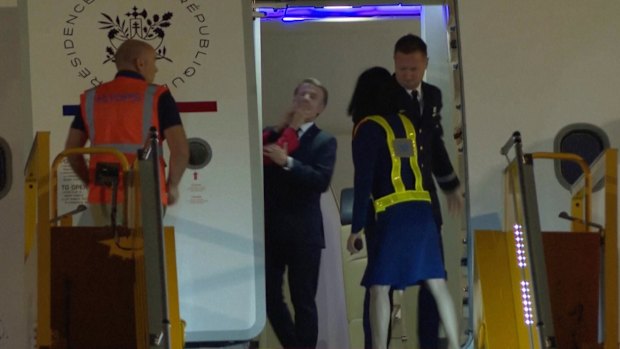 In this grab taken from video, France’s President Emmanuel Macron’s wife appears to push his face away as they prepare to disembark a plane.