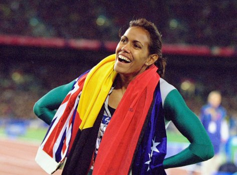 Cathy Freeman takes the Australian and Aboriginal flags on a victory lap after winning gold.