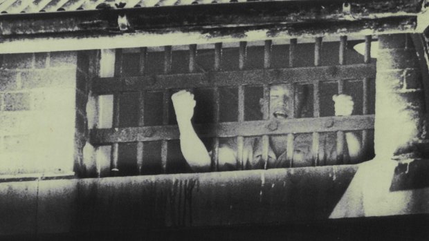 A Boggo Road prisoner holds his fist in defiance after a day of rioting.