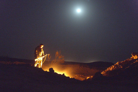 A soldier wanders down to the fire pit where all the rubbish was burnt at Camp Chesty in central Iraq in 2003.